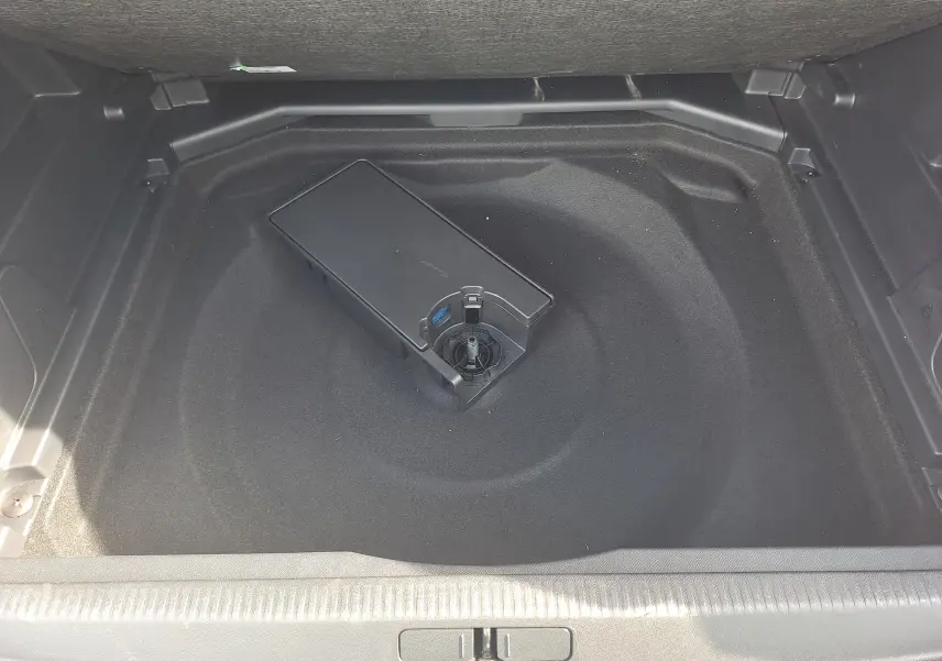 Coffre ouvert du Peugeot 3008 Hybrid 145 gris platinium, vue plongeante sur le rangement sous plancher avec boîte de rangement noire.