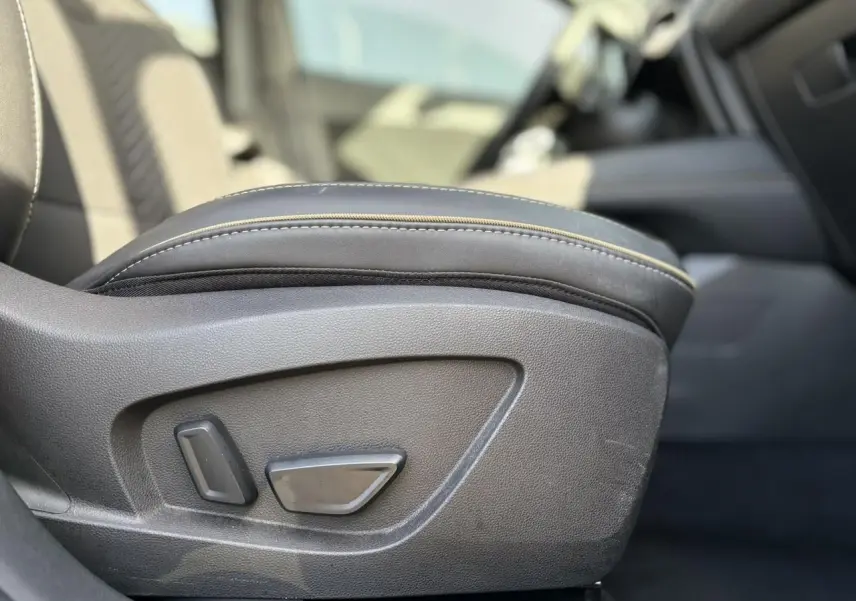 Détail du réglage électrique du siège avant en cuir noir dans l'habitacle d'une Renault SYMBIOZ gris Cassiopée.