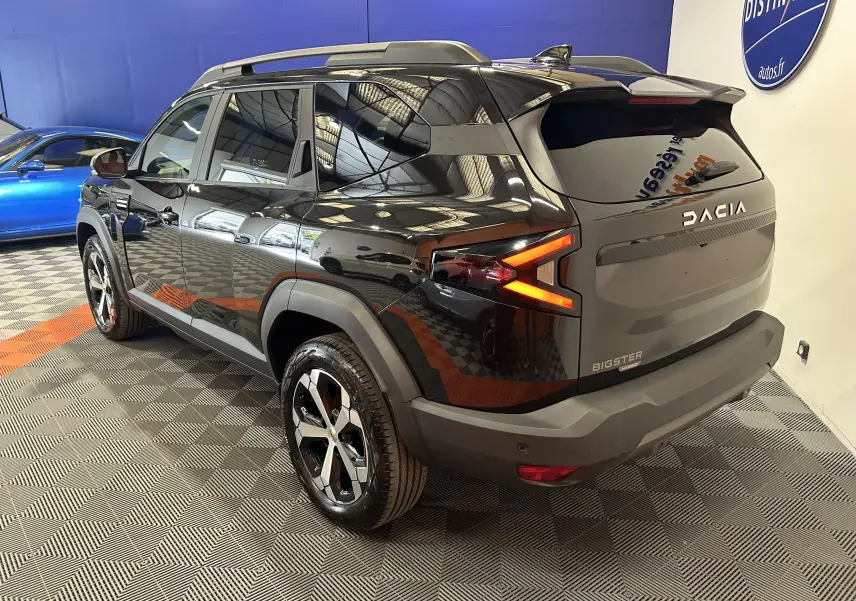 Vue 3/4 arrière droite du Dacia Bigster noir nacré avec feux arrière en forme de flèche et hayon électrique visible.