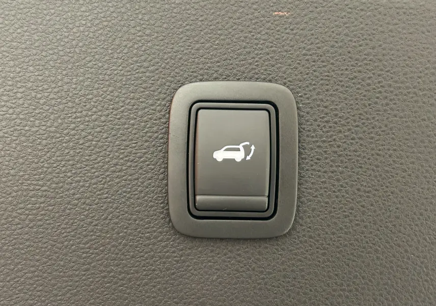 Bouton noir de hayon électrique avec pictogramme blanc, sur tableau de bord intérieur du Dacia Bigster 2026.