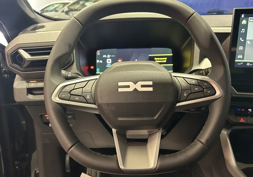 Vue rapprochée du volant multifonction noir du Dacia Bigster 2026 avec tableau de bord digital et écran tactile.