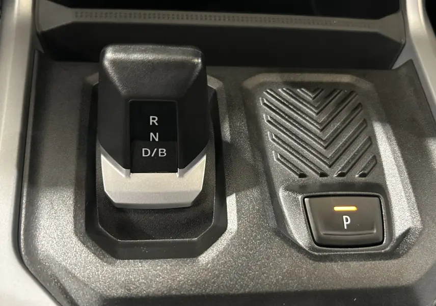 Gros plan sur la commande de boîte automatique et bouton de parking du Dacia Bigster 1.8 Hybrid 155, intérieur noir.