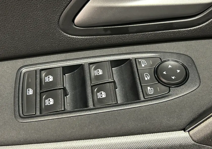 Gros plan sur les commandes des vitres électriques et rétroviseurs côté conducteur du Dacia Bigster 2026 noir nacré.