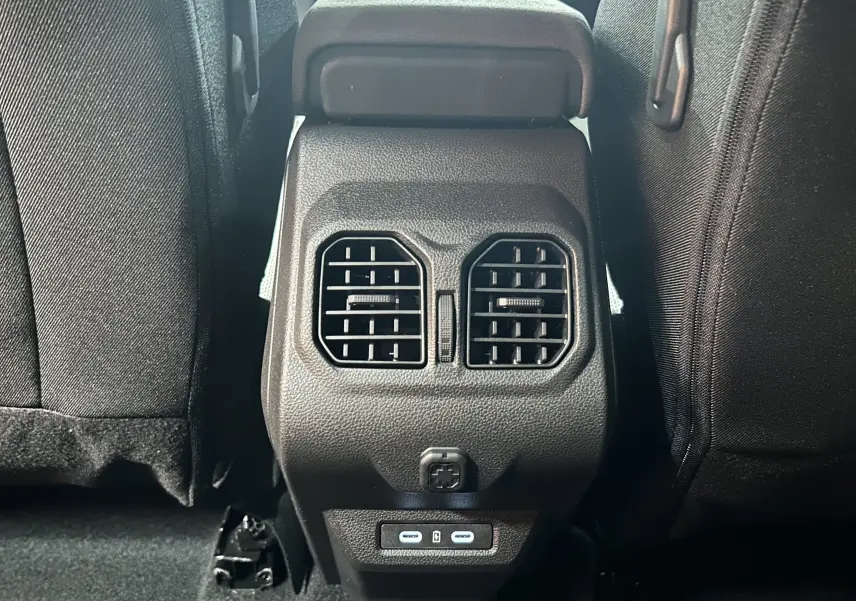 Vue rapprochée des aérateurs arrière et ports USB du Dacia Bigster 1.8 Hybrid 155 Journey, intérieur tissu noir.