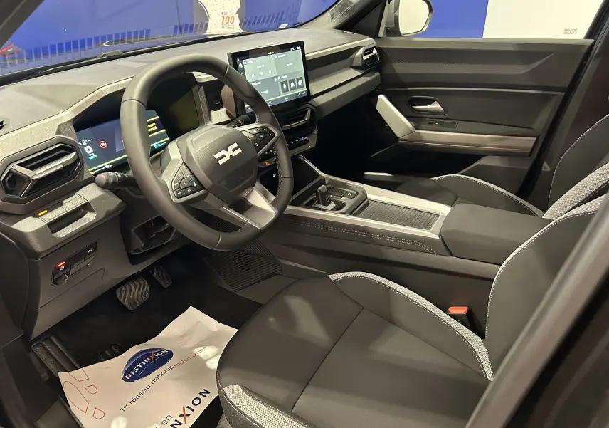Vue intérieure côté conducteur du Dacia Bigster 2026, avec tableau de bord numérique et sellerie tissu noir et gris.