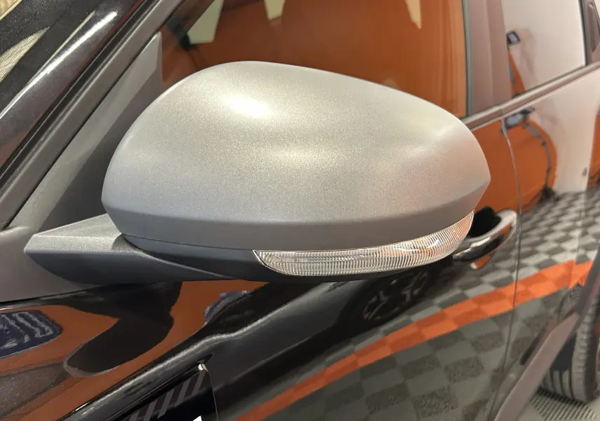 Gros plan sur le rétroviseur gris mat côté conducteur du Dacia Bigster noir nacré, avec clignotant intégré.