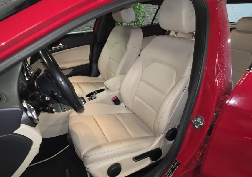 Vue intérieure côté conducteur du Mercedes GLA 200 d rouge, sièges avant en similicuir beige clair.
