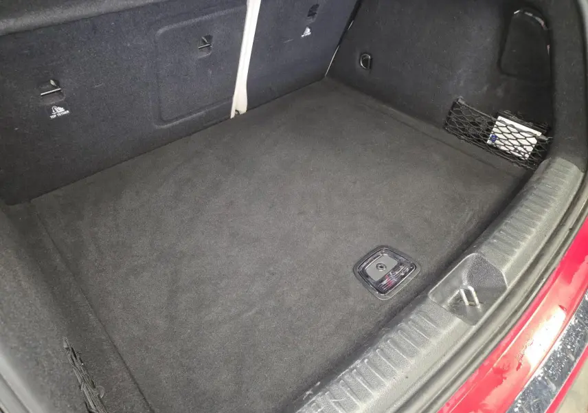 Vue plongeante sur le coffre spacieux et propre d’un Mercedes GLA 200 d rouge avec filet de rangement latéral.