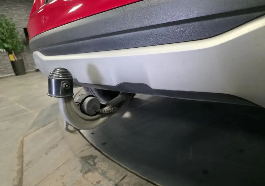 Gros plan sur l'attelage rabattable sous le pare-chocs arrière rouge d'un Mercedes GLA 200 d Inspiration.