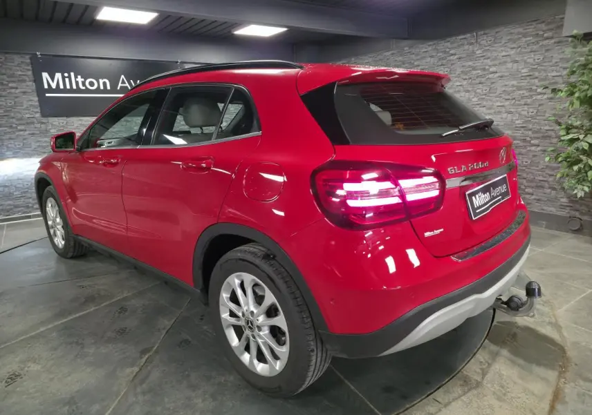 Vue 3/4 arrière droite d'un Mercedes GLA 200 d rouge avec attelage rabattable et jantes alliage 17 pouces.