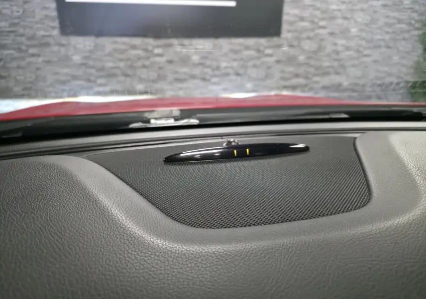 Gros plan sur le tableau de bord noir texturé du Mercedes GLA 200 d rouge, avec haut-parleur central et capteur au centre.
