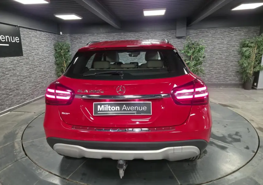 Vue arrière d'un Mercedes GLA 200 d rouge avec attelage rabattable et feux LED allumés dans un showroom.
