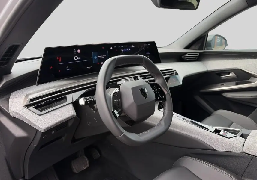 Intérieur du Peugeot 3008 2025 vue côté conducteur, volant cuir et tableau de bord numérique avec finition tissu gris clair.