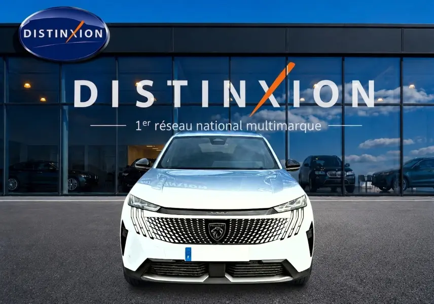Vue frontale d'un Peugeot 3008 blanc 2025 avec calandre distinctive et logo lion visible devant un showroom Distinxion.