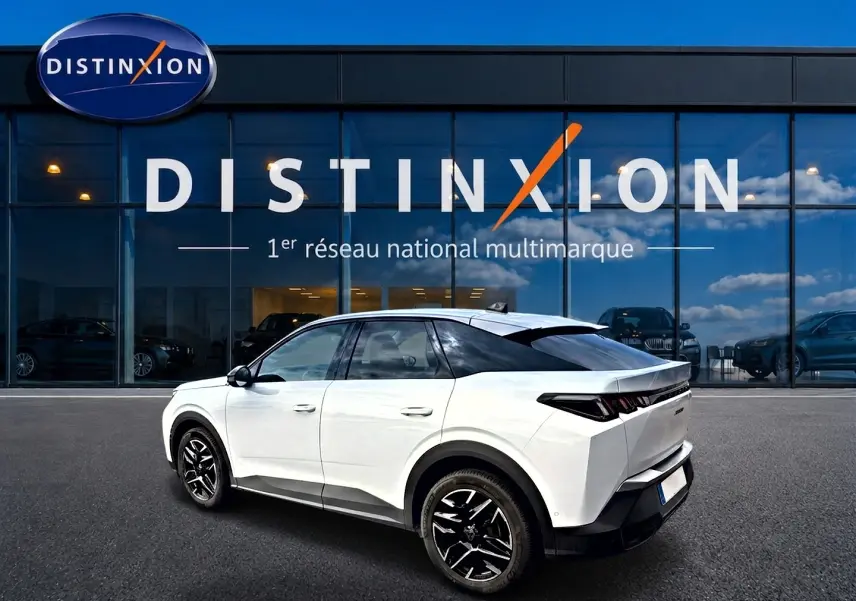 Vue 3/4 arrière droite d’un Peugeot 3008 blanc 2025 avec jantes alu noires devant une vitrine Distinxion.