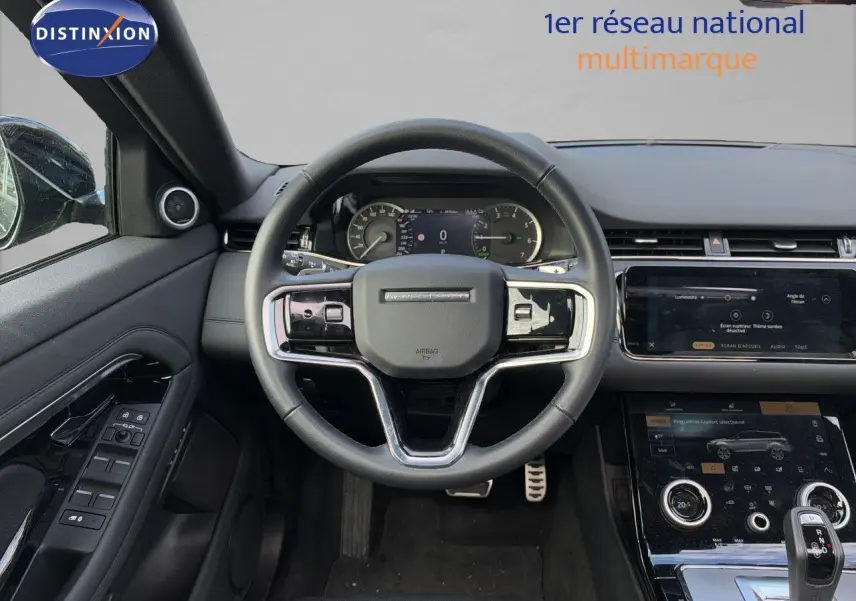 Vue intérieure centrée sur le volant cuir noir du Range Rover Evoque P300e avec tableau de bord et console tactile.