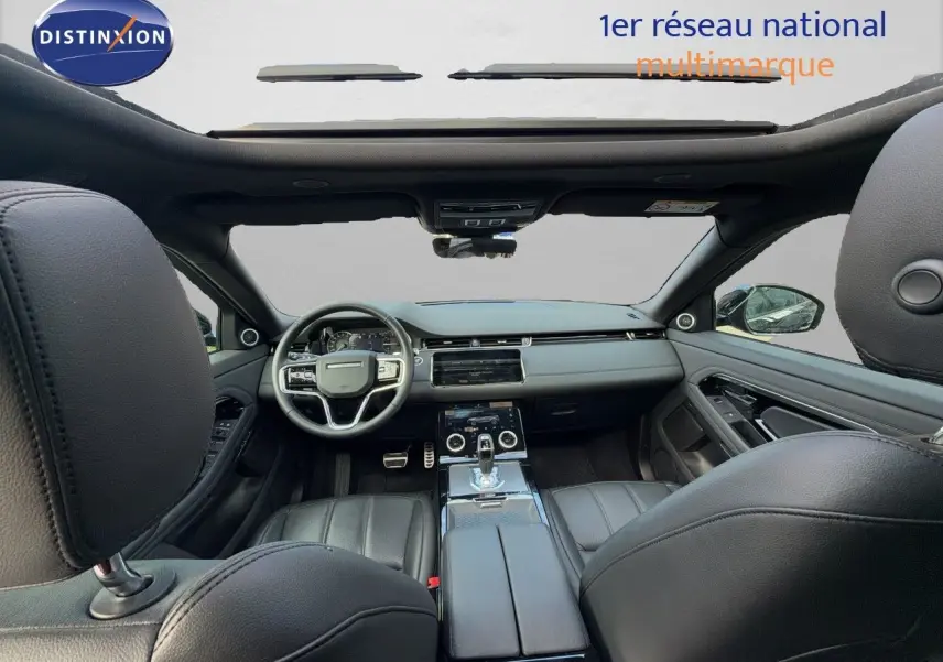 Vue intérieure avant du Range Rover Evoque 2023 en cuir noir, avec tableau de bord moderne et toit panoramique.