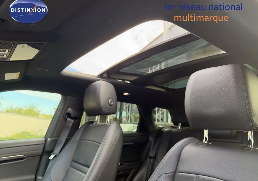 Intérieur du Range Rover Evoque 2023 en cuir noir, vue sur les sièges avant et toit ouvrant panoramique.