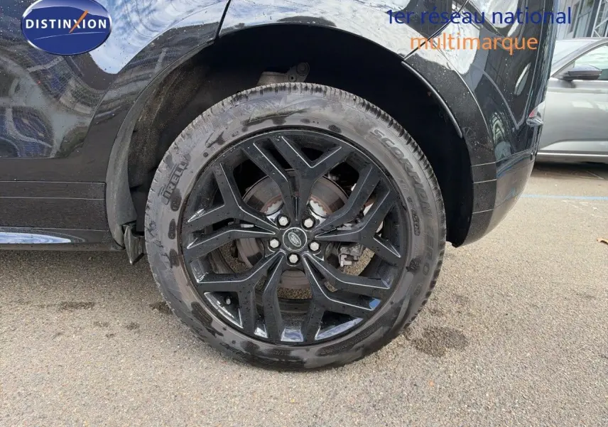 Gros plan sur la roue arrière gauche noire brillante d’un Range Rover Evoque Santorini Black 2023, jante alliage noire.