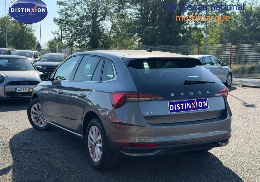 Vue 3/4 arrière droite d'une Skoda Scala gris métallisé avec feux arrière LED et jantes alu en parking extérieur.