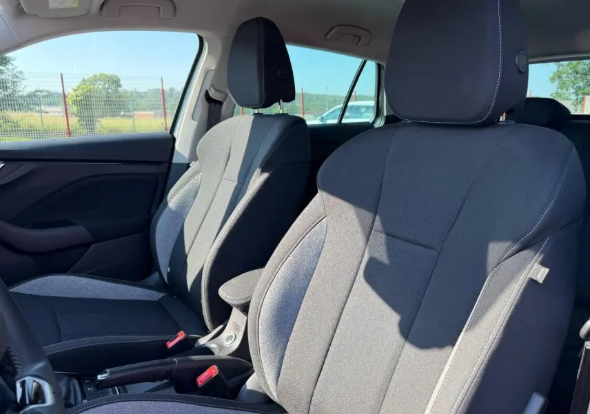 Vue intérieure des sièges avant tissu noir et gris de la Skoda Scala 2025 avec accoudoir central et ceintures rouges.