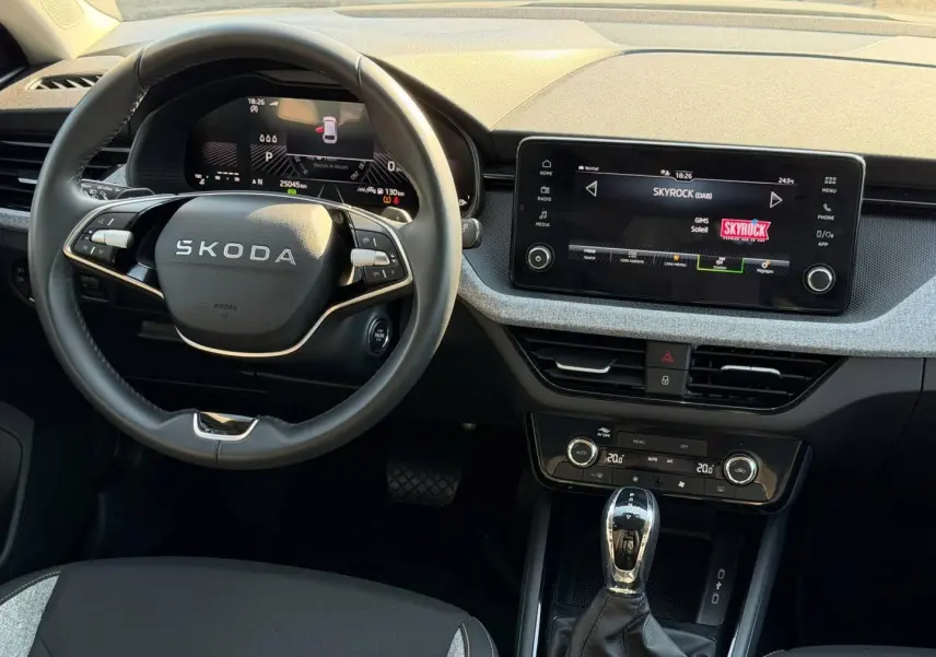 Vue intérieure frontale du poste de conduite gris d'une Skoda Scala 2025 avec écran tactile et volant multifonction.