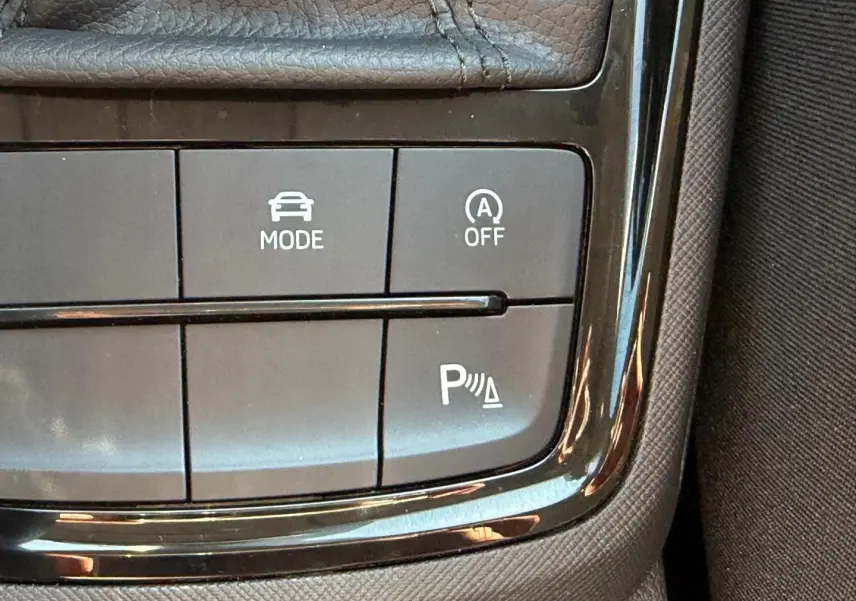Gros plan sur les commandes de mode de conduite et assistance au stationnement d'une Skoda Scala gris 2025.