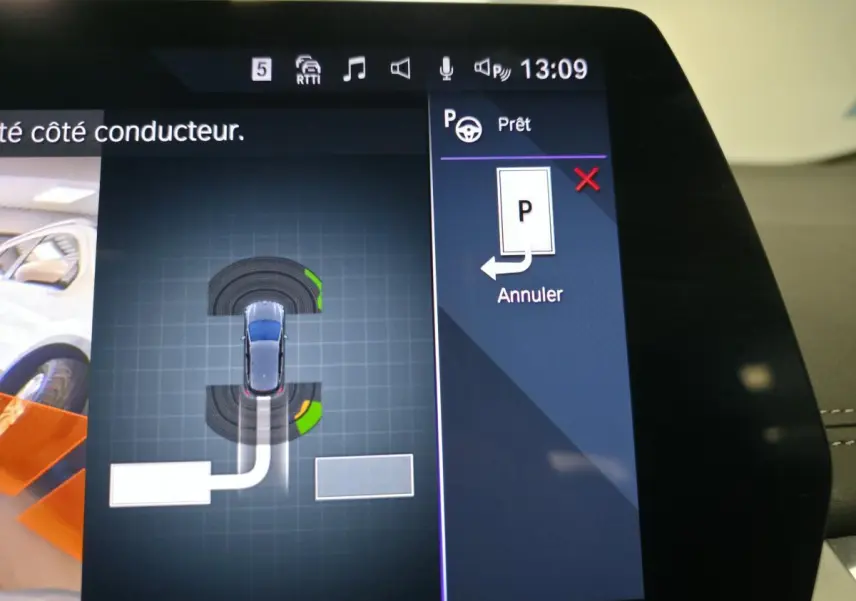 Écran tactile incurvé de la BMW Série 2 218i Active Tourer affichant l'aide au stationnement en vue de dessus du véhicule gris.