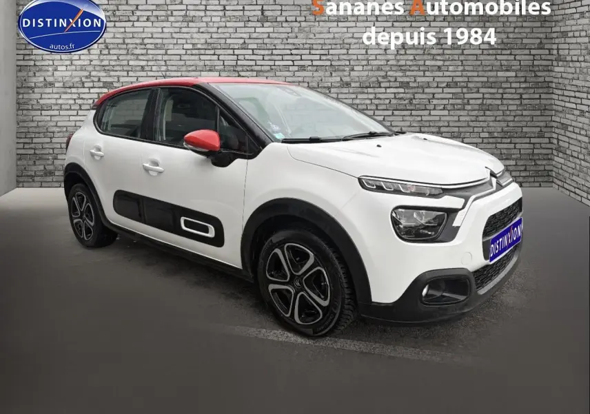 Citroën C3 blanc toit rouge vue 3/4 avant droit avec enjoliveurs noirs et rétroviseurs rouges.