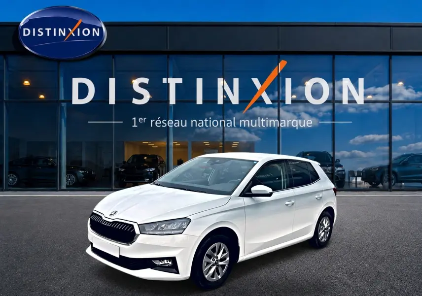 Vue 3/4 avant droite d'une Skoda Fabia blanche 2025 garée devant une vitrine Distinxion.