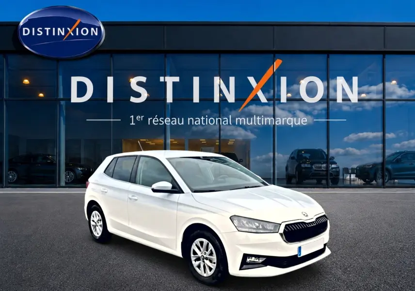 SKODA Fabia blanche vue en 3/4 avant droit, avec jantes alu et calandre noire devant un showroom Distinxion.