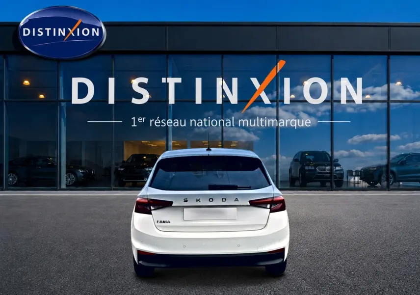 Vue arrière d'une Skoda Fabia blanche 2025 stationnée devant une vitrine avec logo Distinxion.