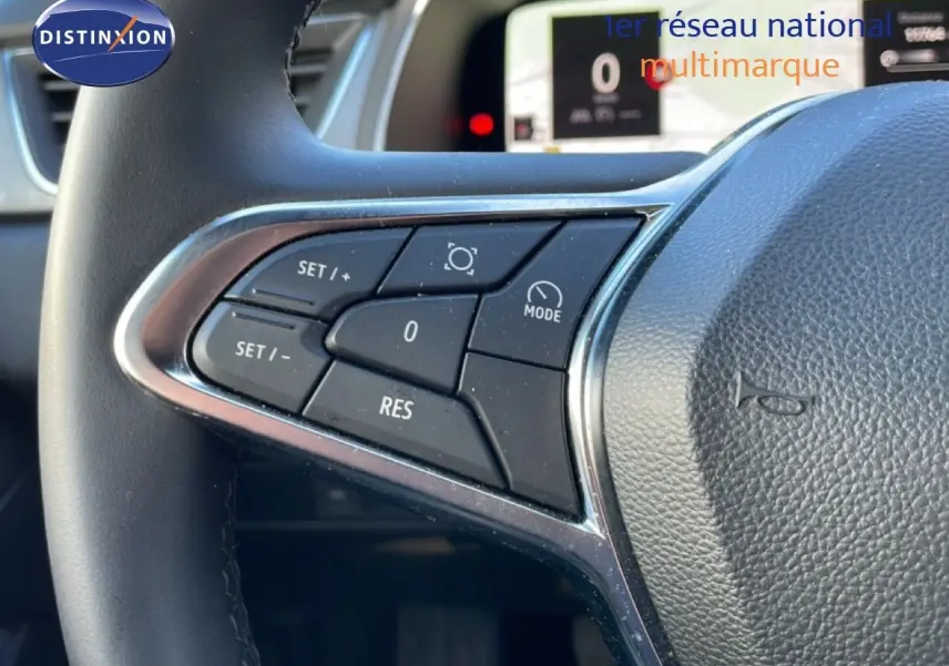 Gros plan sur les commandes au volant côté gauche du Renault Captur gris Rafale métal 2025 avec affichage numérique en arrière-plan.