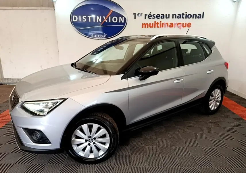SEAT Arona gris clair vue 3/4 avant droit en intérieur, avec toit noir et jantes alliage.