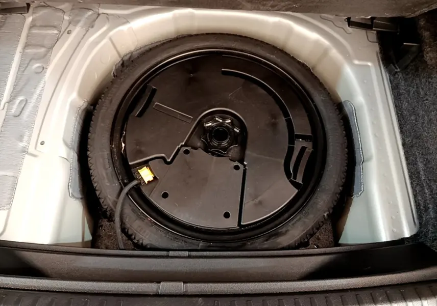 Vue plongeante sur la roue de secours noire dans le coffre d’un SEAT Arona gris clair de 2019.