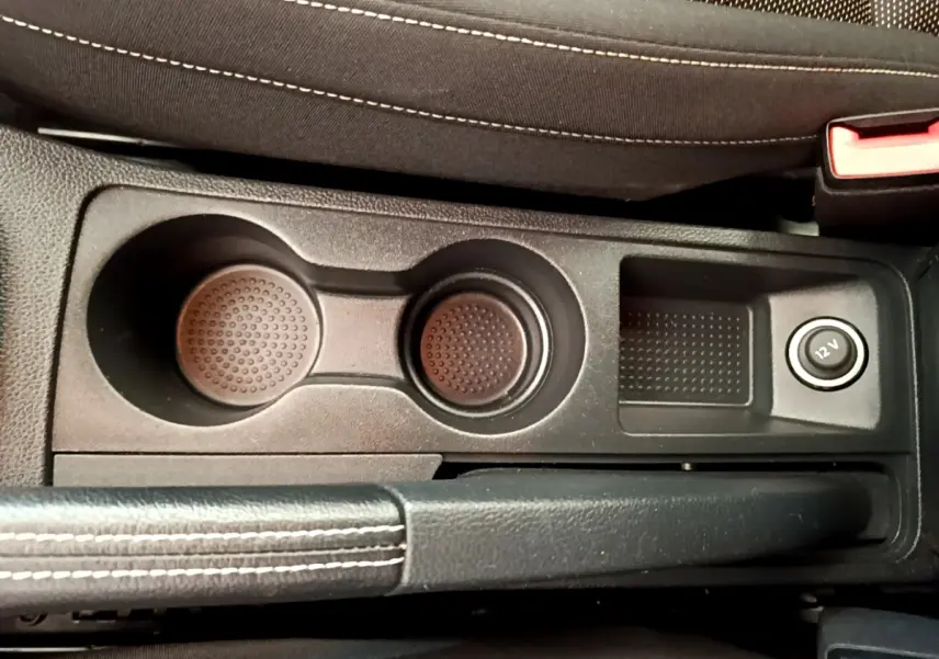Vue rapprochée de la console centrale noire avec porte-gobelets et prise 12V du SEAT Arona gris clair 2019.