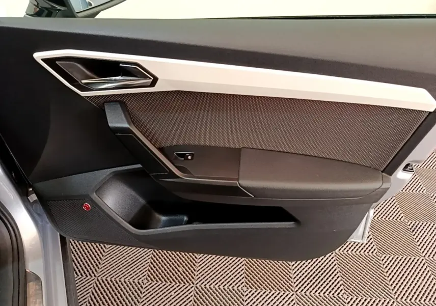 Vue intérieure côté gauche de la porte avant gris clair du SEAT Arona avec garniture noire et insert argenté.