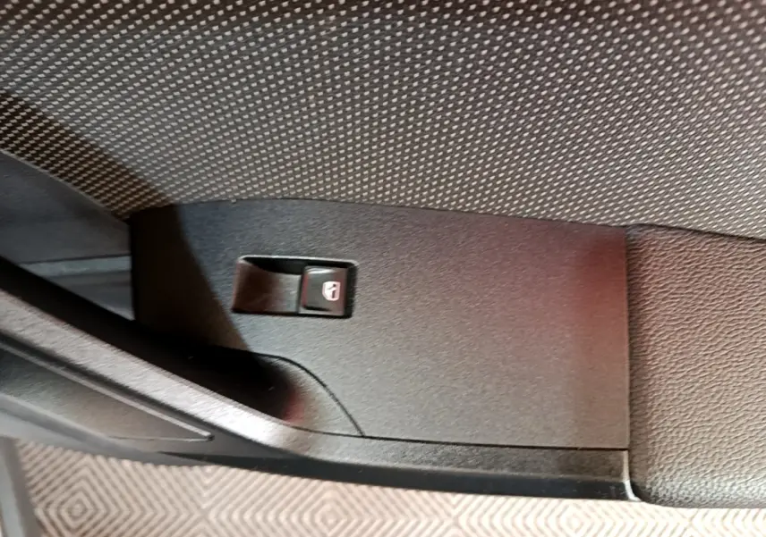 Gros plan sur le bouton de verrouillage des portes côté intérieur d'une SEAT Arona gris clair.