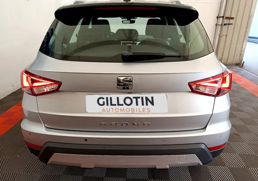 Vue arrière d'un SEAT Arona gris clair 2019 avec feux LED allumés et logo central visible.