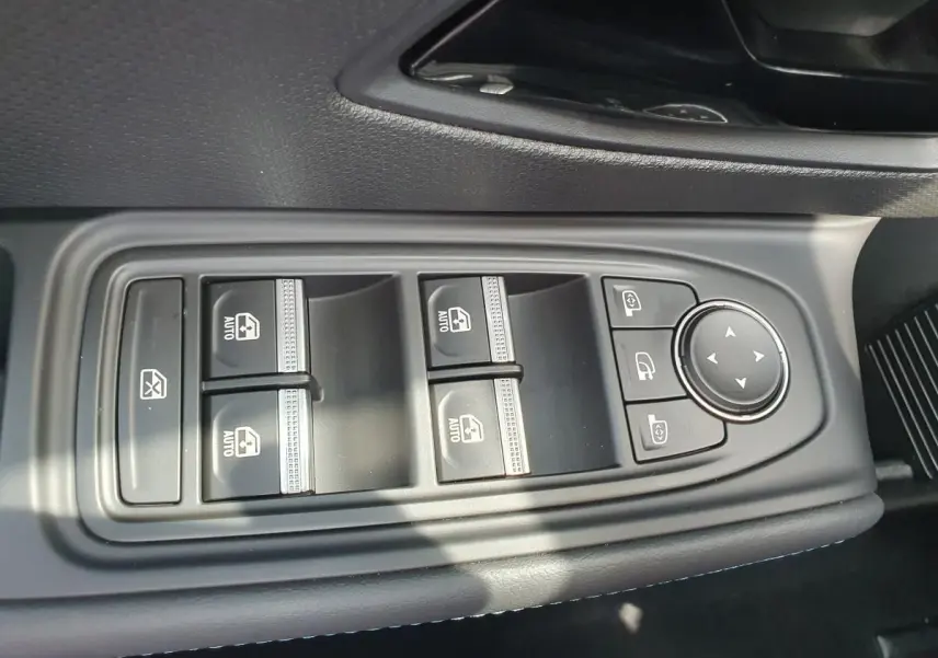 Gros plan sur les commandes des vitres électriques et réglages des rétroviseurs côté conducteur d'une Renault Clio VI gris Rafale.