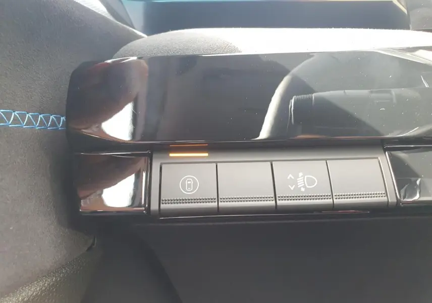 Détail des commandes d’éclairage et verrouillage sur la console intérieure noire de la Renault Clio VI hybride.