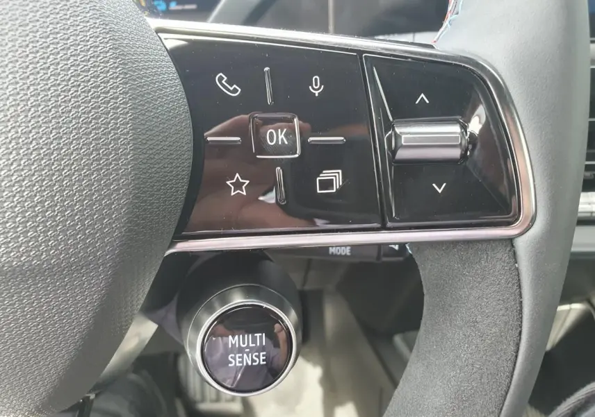 Gros plan sur les commandes au volant de la Renault Clio VI gris Rafale, avec bouton Multi-Sense et touches multifonctions.