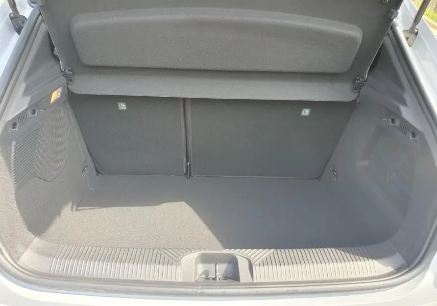 Coffre ouvert vu de l'arrière d'une Renault Clio VI gris Rafale, montrant un espace de chargement vide et propre.