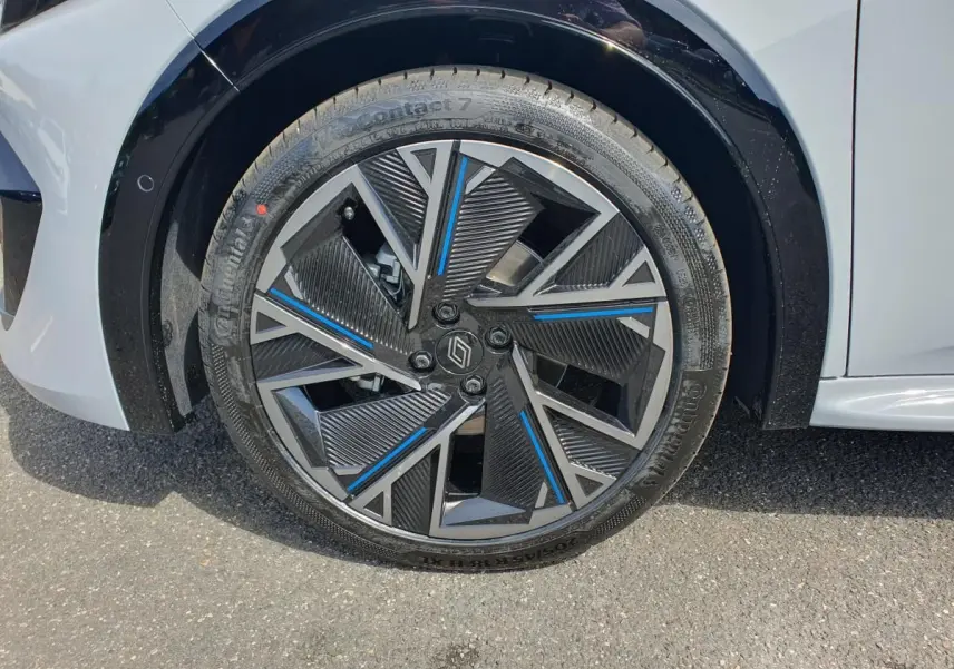 Gros plan sur la jante alliage 18” diamantée noire et bleue du côté avant droit de la Renault Clio VI gris Rafale.
