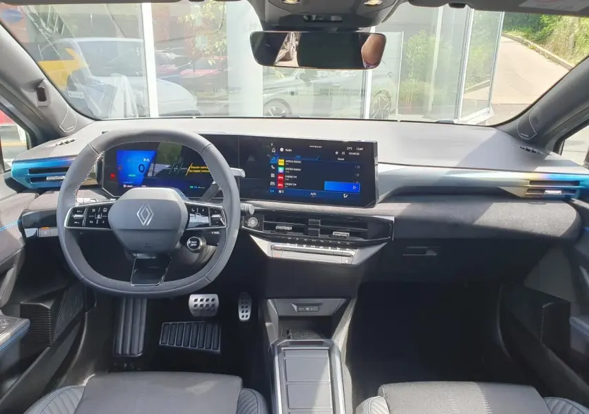 Vue frontale de l’habitacle de la Renault Clio VI gris Rafale, avec tableau de bord numérique et volant multifonctions.