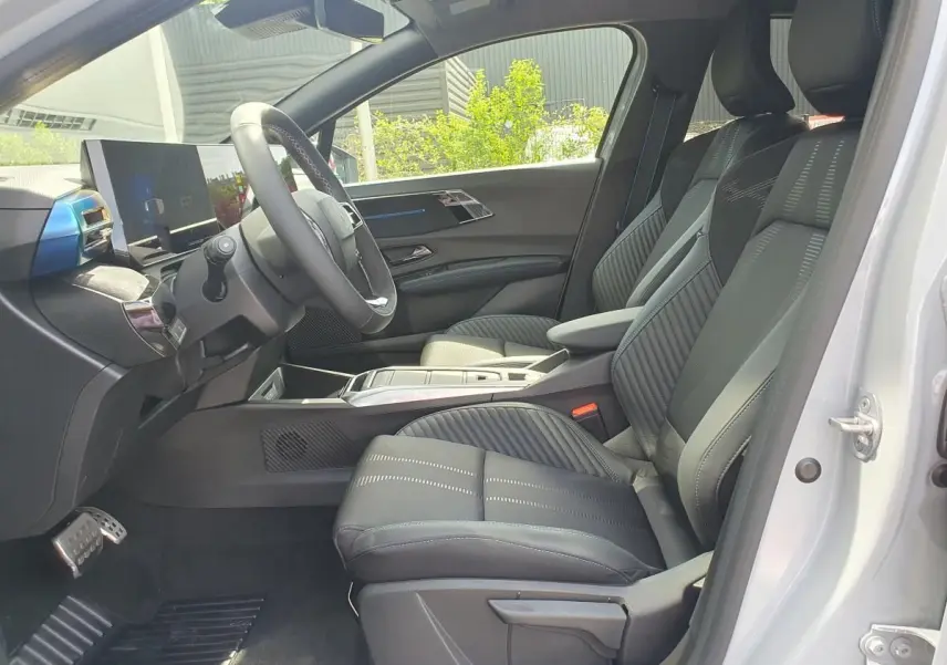 Vue intérieure côté conducteur de la Renault Clio VI gris Rafale, avec sièges en tissu noir et tableau de bord moderne.