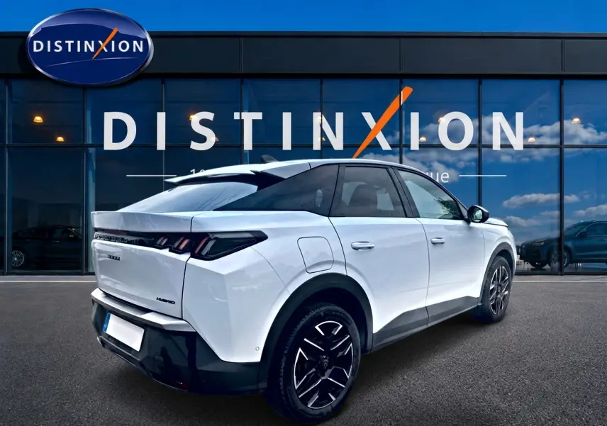 Vue 3/4 arrière droite d'un Peugeot 3008 blanc avec jantes alu noires devant une vitrine Distinxion.