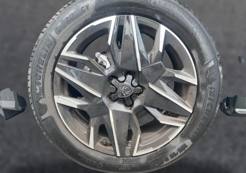 Gros plan sur la jante alu noire et argentée d’un Peugeot 3008 blanc, avec logo lion au centre.