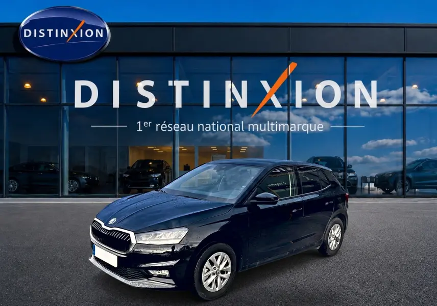SKODA Fabia noire vue en 3/4 avant droit, avec jantes alu et calandre chromée devant un showroom Distinxion.