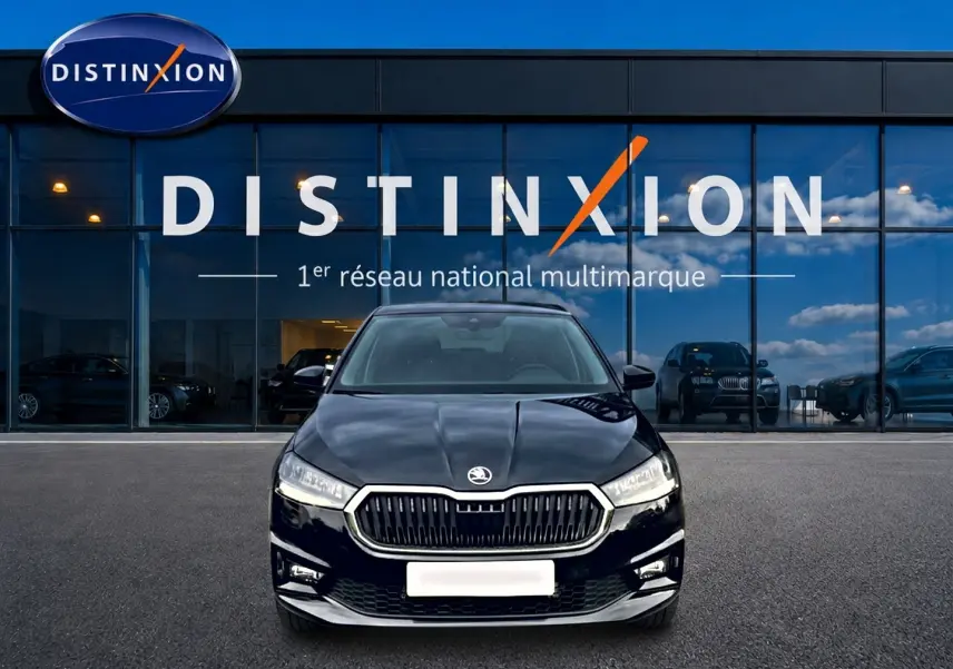 Vue frontale d'une Skoda Fabia noire 2025 garée devant une vitrine avec logo Distinxion en arrière-plan.
